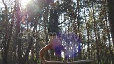 强壮的肌肉男在森林里做倒立。 肌肉男健身男在木头上做特技。 运动员